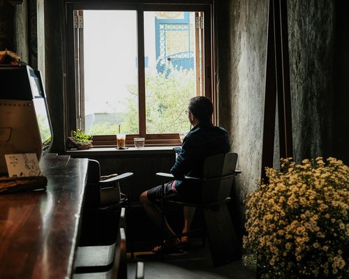 Person relaxing thoughtfully by a bright window looking at nature
